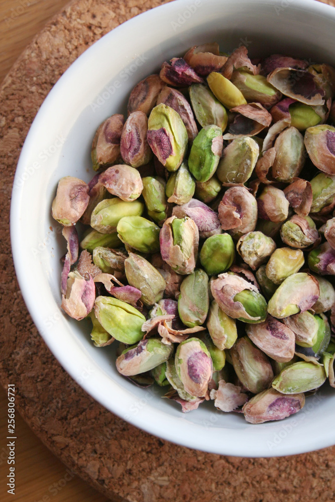 Shelled pistachios in a bowl on wooden table Shelled pistachios in a bowl on wooden table