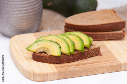 Avocado slices on the toasted dark bread with a salt. Healthy snack.