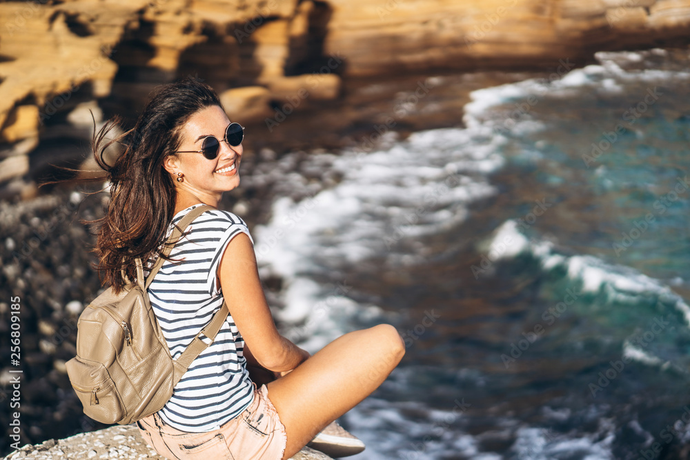 Pretty long hair tourist girl relaxing on the stones near sea. Pretty long hair tourist girl relaxing on the stones near sea.