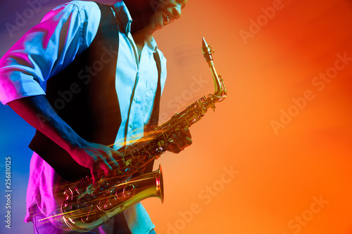 Photography African American handsome jazz musician playing the saxophone in the studio on a neon background