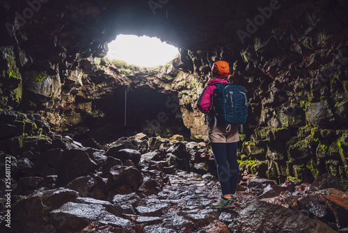 Woman traveler explore lava tunnel in Iceland. Raufarholshellir is a beautiful hidden world of cave. It is one of the longest and best-known lava tubes in Iceland, Europe for incredible adventure. photo