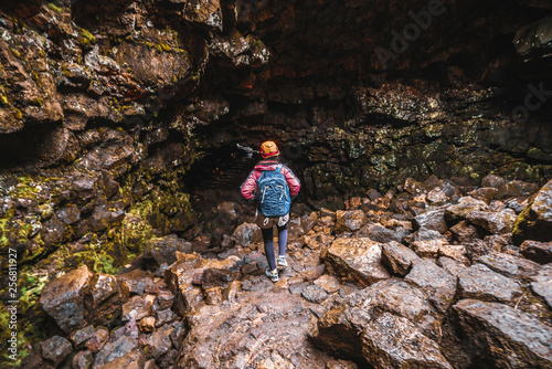 Woman traveler explore lava tunnel in Iceland. Raufarholshellir is a beautiful hidden world of cave. It is one of the longest and best-known lava tubes in Iceland, Europe for incredible adventure. photo