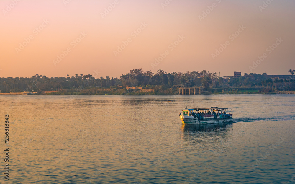 Pleasure boats and ferries in the channel of the Nile River, the capital of Egypt-Cairo. On the background-the industrial panorama of the city shrouded in dirty air Pleasure boats and ferries in the channel of the Nile River, the capital of Egypt-Cairo. On the background-the industrial panorama of the city shrouded in dirty air
