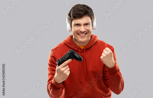 technology, gaming and people concept - young man or gamer in headphones with gamepad playing video game photo