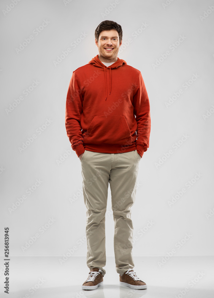 people concept - smiling young man in red hoodie over grey background people concept - smiling young man in red hoodie over grey background
