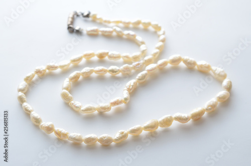 A necklace of white pearls on white background