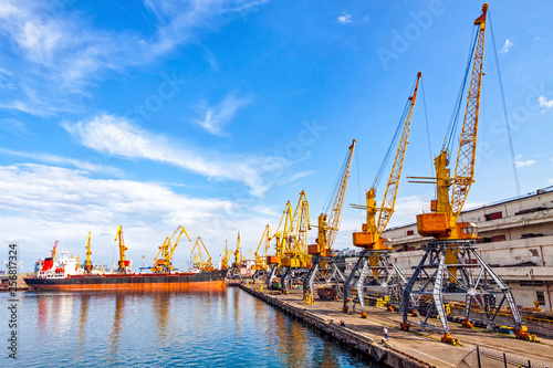 Lifting cargo cranes, ship and grain dryer in Sea Port of Odessa, Black Sea, Ukraine. Odessa Marine Trade Port is the largest Ukrainian seaport and one of the largest ports in the Black Sea basin photo