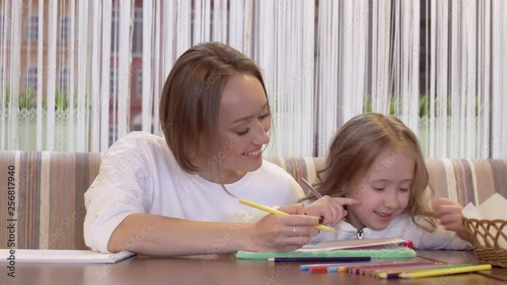 Positive Young Woman Is Drawing With Her Little Beautiful Daughter Positive Young Woman Is Drawing With Her Little Beautiful Daughter