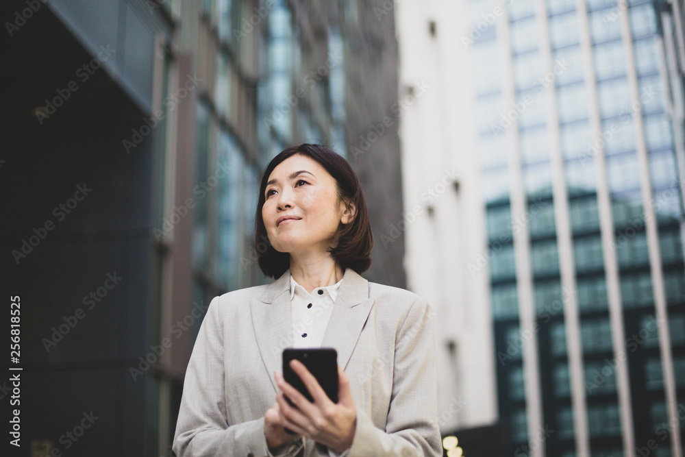 Businesswoman walking in city using smartphone Businesswoman walking in city using smartphone