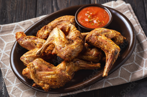 Grilled rabbit legs with spicy tomato dip.