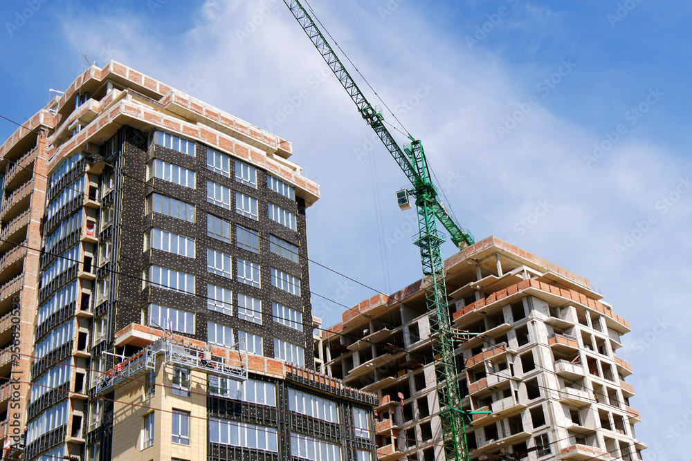 Construction of a multi-storey residential complex. Crane near the building under construction. Background construction site.