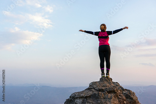 Woman standing on rock cliff with horizon and sky background