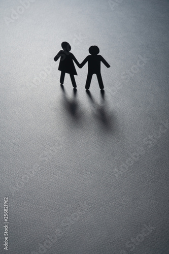 Paper figure of a couple holding hands on gray surface. Loneliness, childless, old age concept. photo