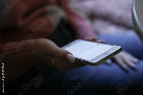 Mockup image of woman's hands holding white mobile phone with blank screen on thigh