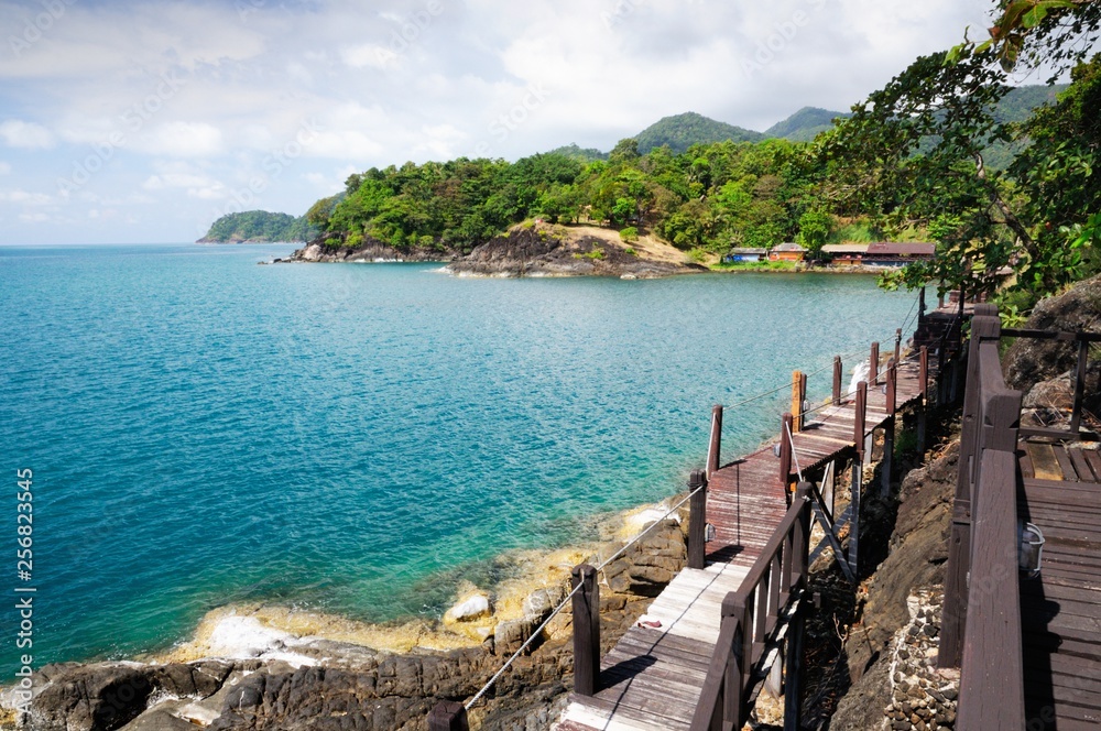 Wooden pathway and tourist resort at the volcanic coastline of the tropical Koh Chang Island, Thailand.