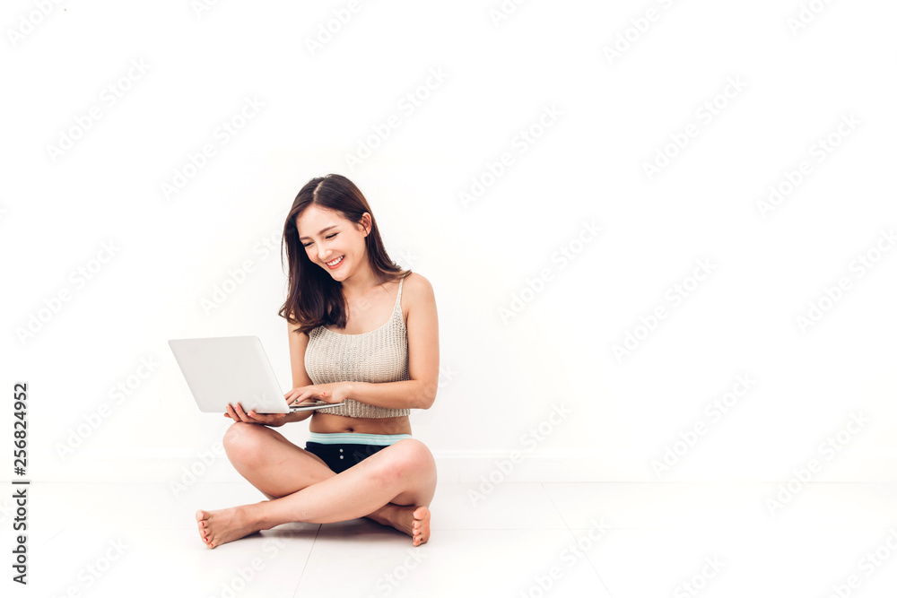Beautiful woman using digital laptop computer checking social apps and working sitting on the floor against copy space for adding text with white wall background.wireless technology concept Beautiful woman using digital laptop computer checking social apps and working sitting on the floor against copy space for adding text with white wall background.wireless technology concept