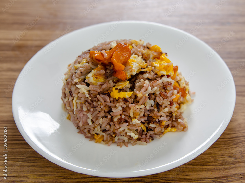 Fried brown rice with eggs and sausages on white dish. Fried brown rice with eggs and sausages on white dish.