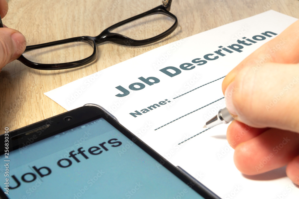 Job Description with Hand, smartphone and Pen on the table. Job Description with Hand, smartphone and Pen on the table.