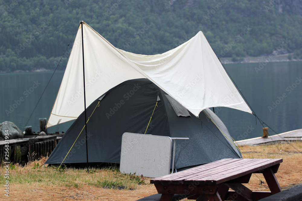 Tent under awning on a camping ground, Norway. Rainy weather at scandinavian fjords.