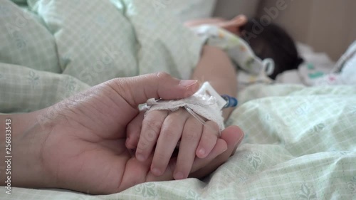 Mother holding hand of his daughter was sick in bed at the hospital. Handheld shot. 4K