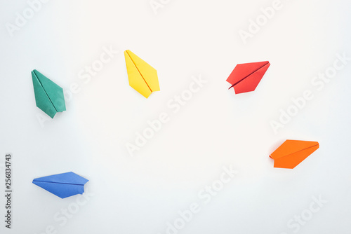Top view of colorful paper planes on white surface