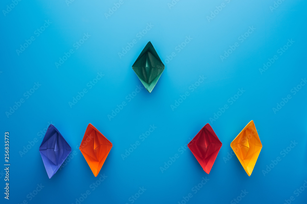 Flat lay with colorful paper boats on blue surface Flat lay with colorful paper boats on blue surface