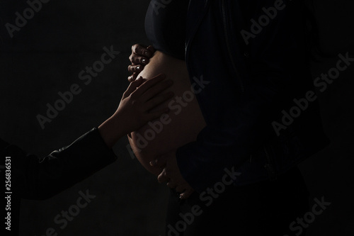 Close Up of pregnant woman's belly, side view. silhouette of Pregnant woman on a black background.