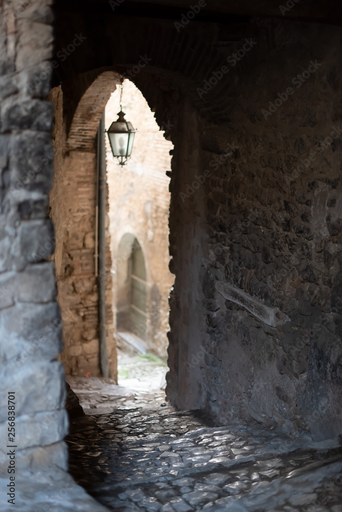 Passage between arches in a downhill street in an historic center in Italy
