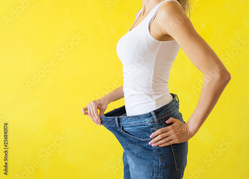 Woman showing her big trousers after successful diet and weight loss photo