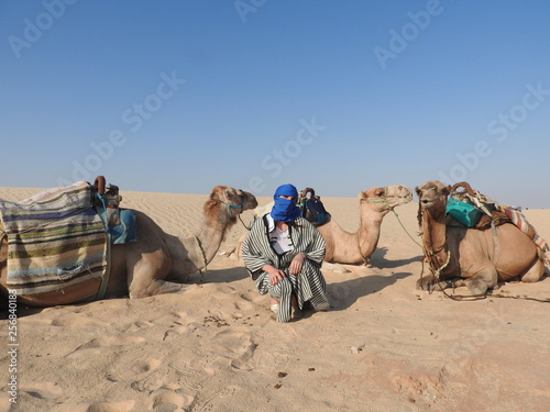 the woman in the turban  the face is closed  with a camel in the Sahara desert.