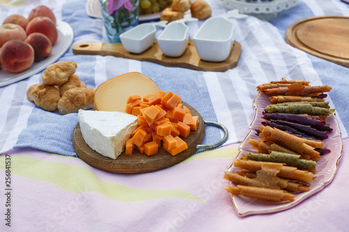 wooden tray with cheese assorti, pastillum rolls and croissant layout on blue picnic blanket. healthy food weekends photo
