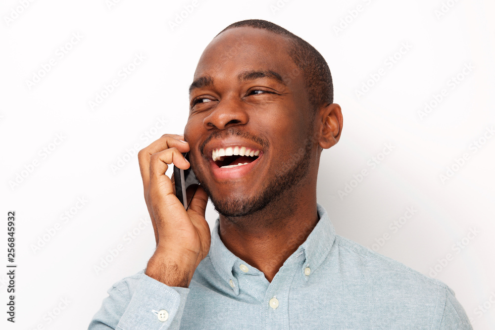 Close up smiling young black man talking with cellphone against isolated white background Close up smiling young black man talking with cellphone against isolated white background