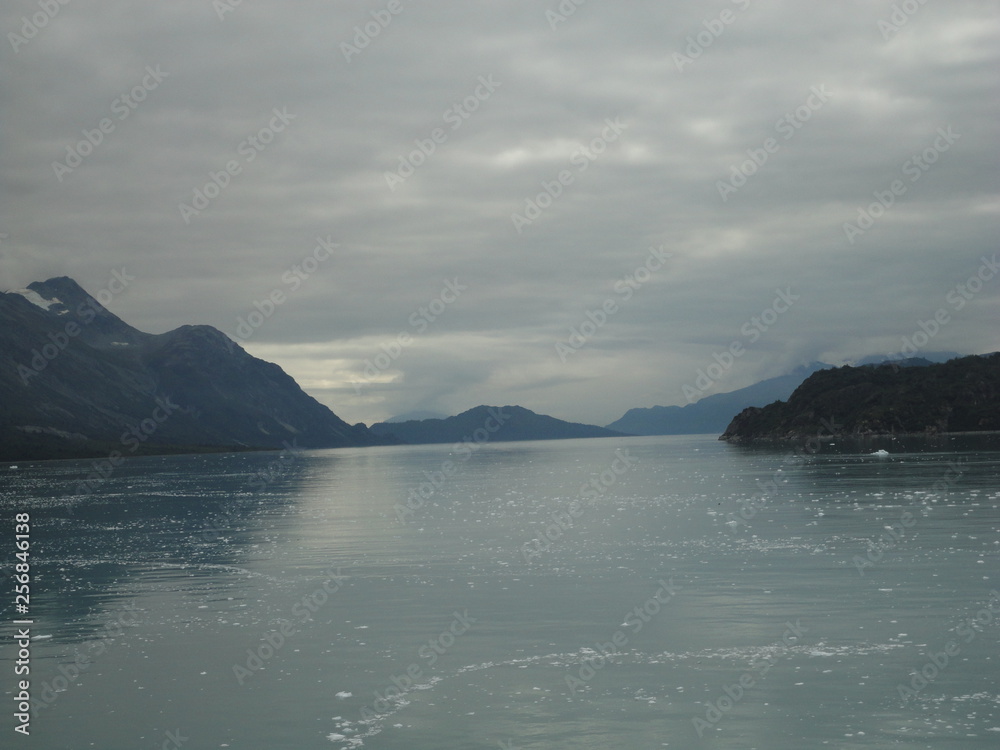 Passage in the Pacific Ocean between two mountain ranges. Calm peaceful waters flowing slowly under a cloudy sky.