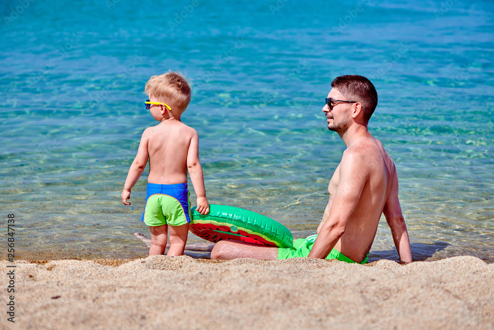 Toddler boy on beach with father Toddler boy on beach with father