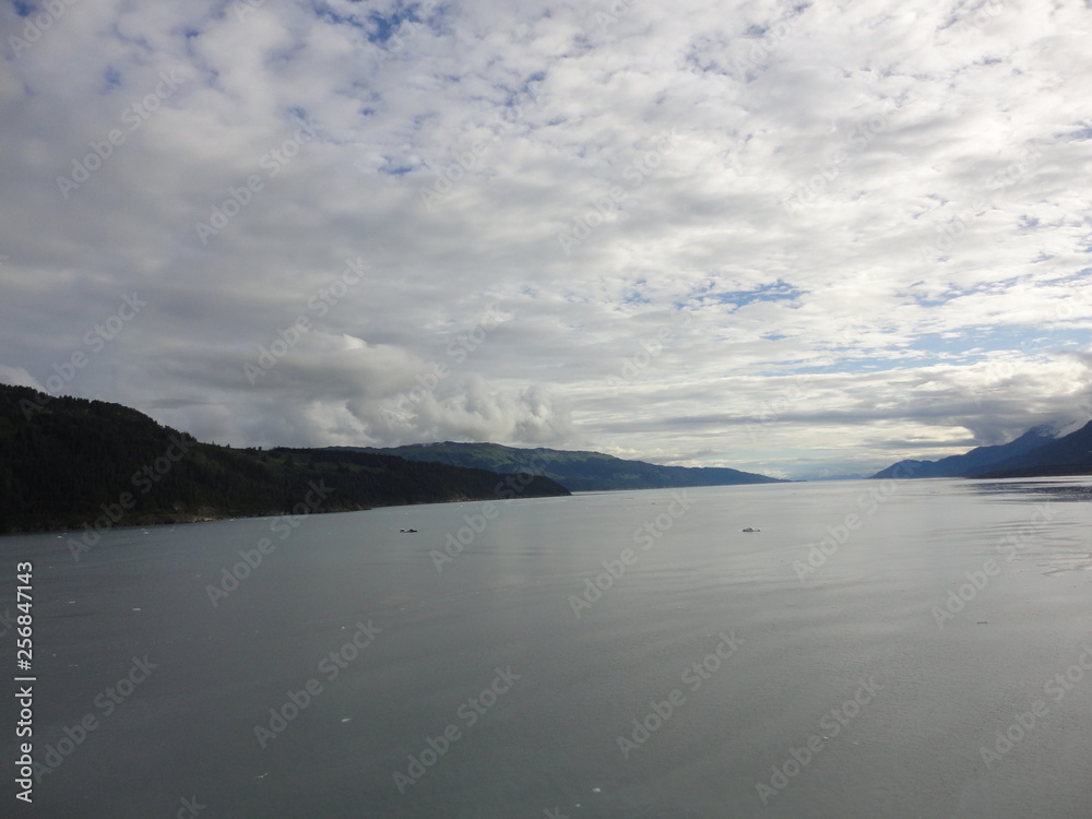Passage in the Pacific Ocean between two mountain ranges. Calm peaceful waters flowing slowly under a cloudy sky.