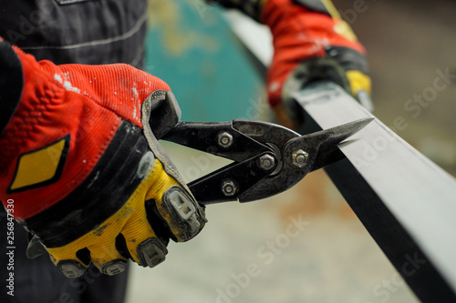 Young male construction worker and repairman working with a screwdriver and metal profile.