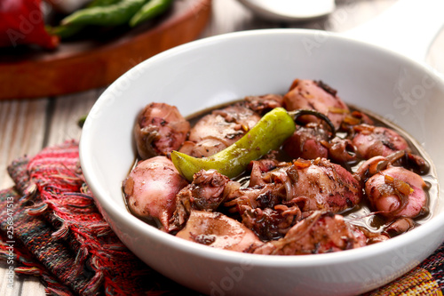 A tasty squid dish with soy sauce in white bowl. Adobong Pusit from Philippines.
