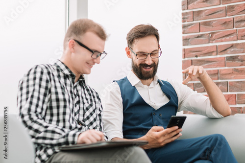 Two business people partners watching media content on a smartphone