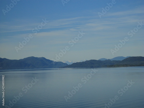 Calm Pacific Ocean in the inside passage in Alaska blue sky meets mountains and blue sea in a peacefully clear view