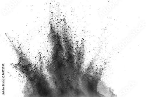 Black powder explosion against white background. Charcoal dust particles exhale in the air.