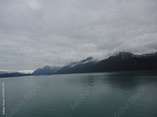 Mountain Filled horizon on the pacific ocean. Inside passage Alaska with glaciers at the peaks under a cloudy sky © Justin