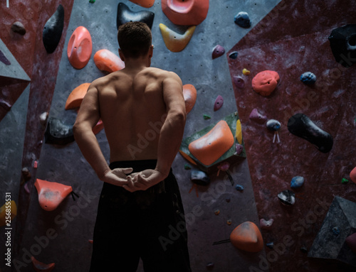 Athletic man stretching before climbing in a bouldering gym