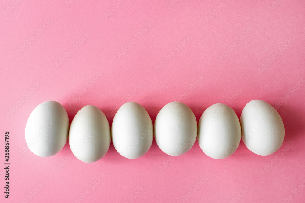 six empty white chicken eggs beside on a pale pink background six empty white chicken eggs beside on a pale pink background