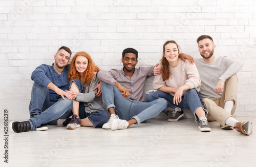 Diverse students sitting on floor and looking at camera