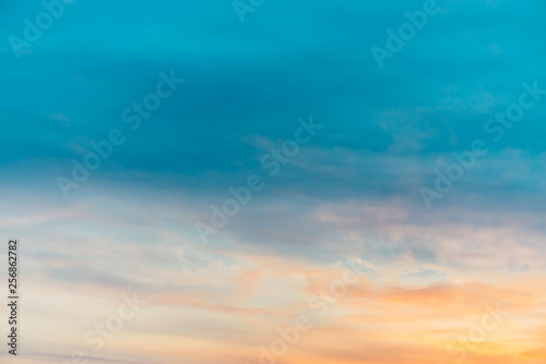 Sunset sky with orange yellow light clouds. Colorful smooth blue sky gradient. Natural background of sunrise. Amazing heaven at morning. Slightly cloudy evening atmosphere. Wonderful weather on dawn.