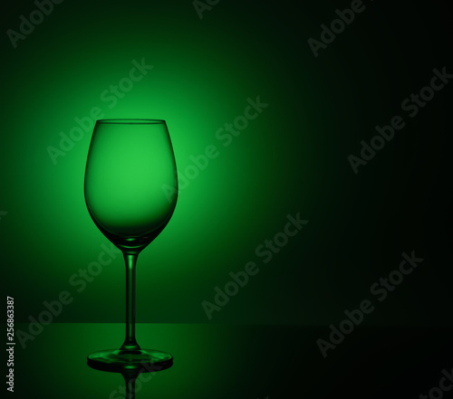 Empty wine glass is on acrylic glass, on a green background
