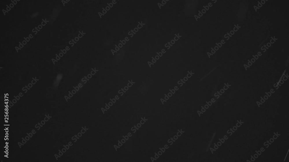 White particles and ink slowly moving in water on black background