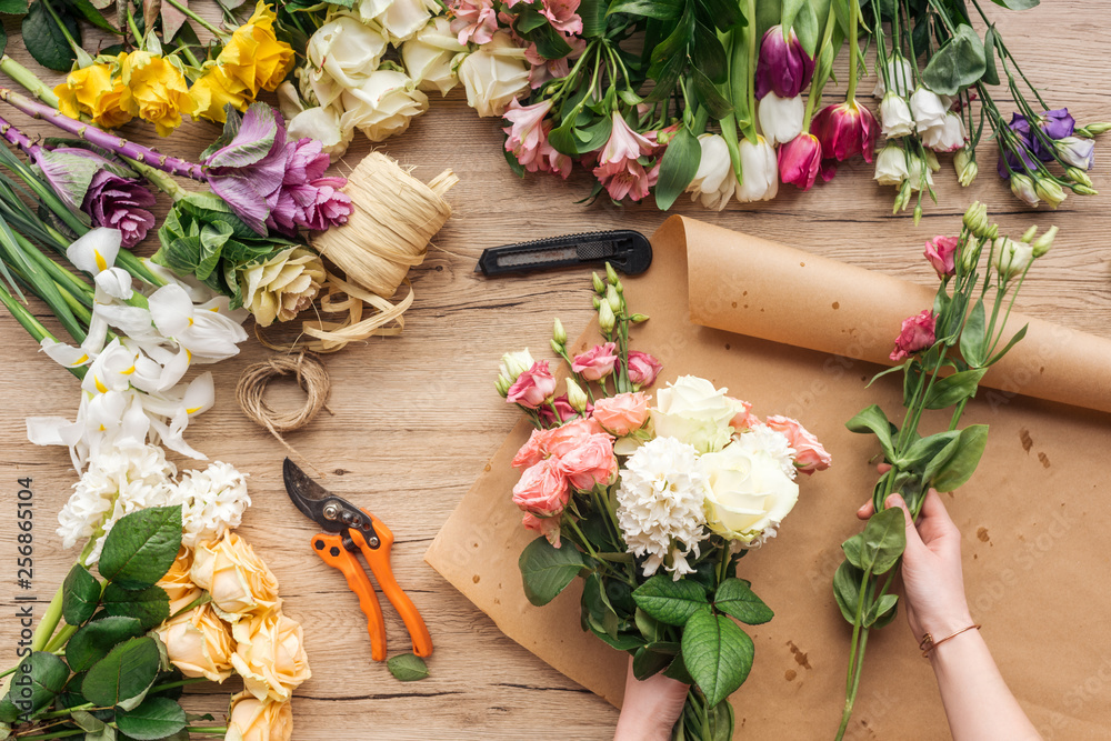 Partial view of florist making flower bouquet on wooden surface - obrazy, fototapety, plakaty 