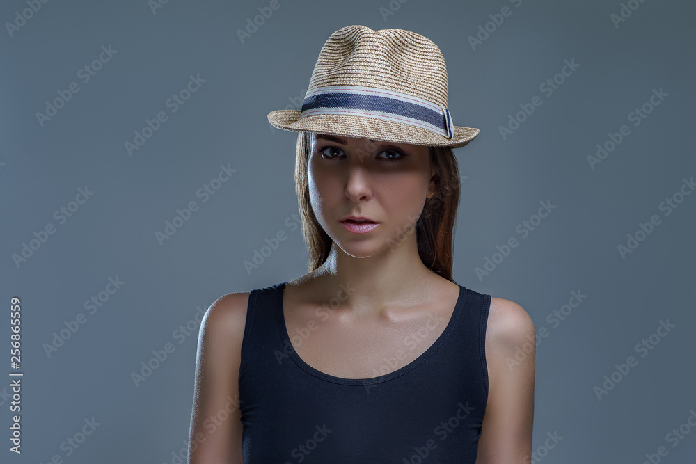 Beautiful brunette woman in a black shirt and fashion hat isolated on gray background in studio Beautiful brunette woman in a black shirt and fashion hat isolated on gray background in studio