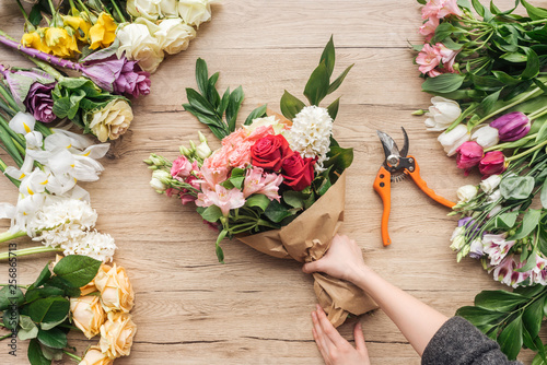Schilderij op canvas Cropped view of florist making flower bouquet on wooden surface